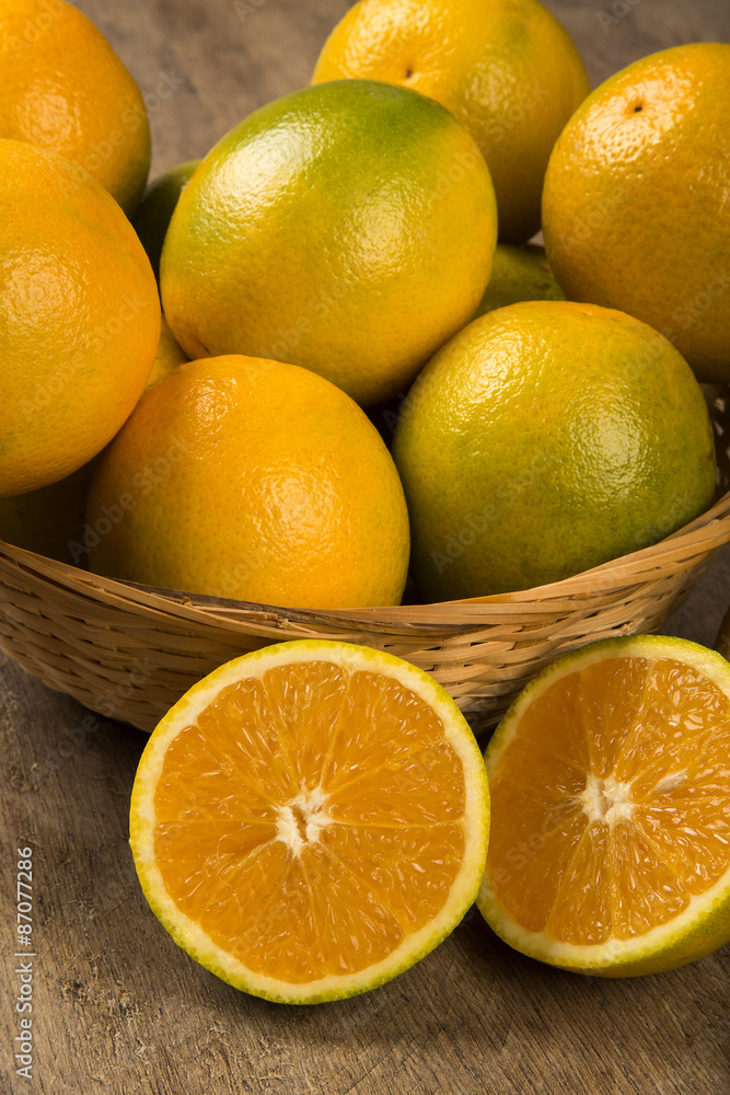 Close up of some oranges in a basket over a wooden surface Close up of some oranges in a basket over a wooden surface