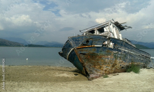 Shipwrecked wood boat on beach	 photo