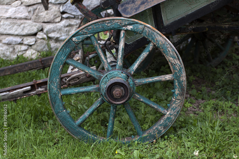 Wooden wheel and hay on meadow