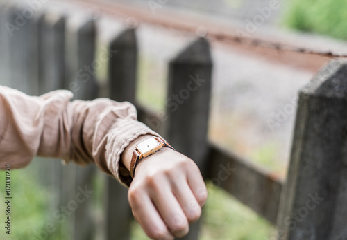 線路の横で腕時計を見る女性