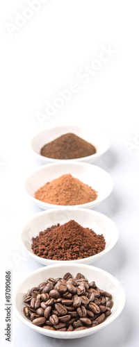 Coffee beans, powdered coffee, chocolate powder and processed tea leaves beverages in white bowl over white background