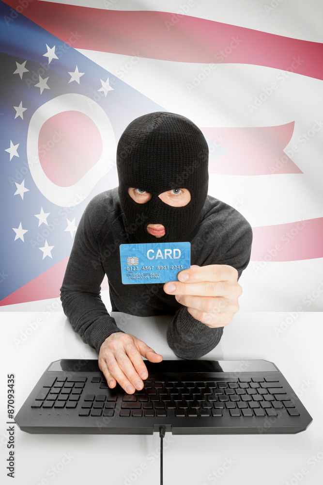 Hacker holding credit card with US state flag on background - Ohio Hacker holding credit card with US state flag on background - Ohio