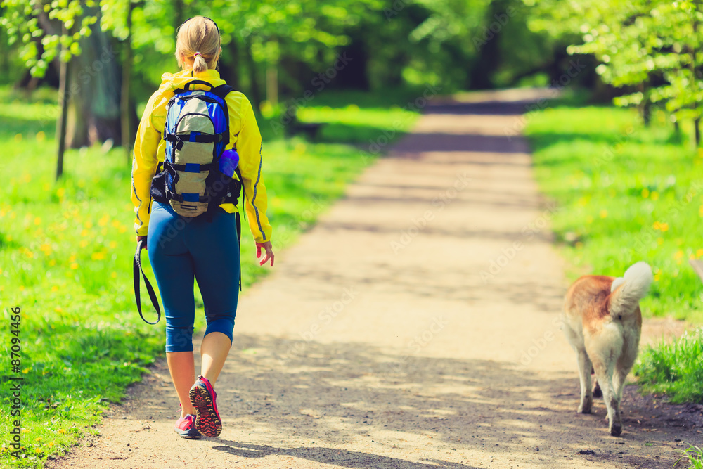 Obraz premium Woman runner walking with dog in summer park