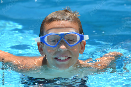 boy with goggles in swimming pool having fun