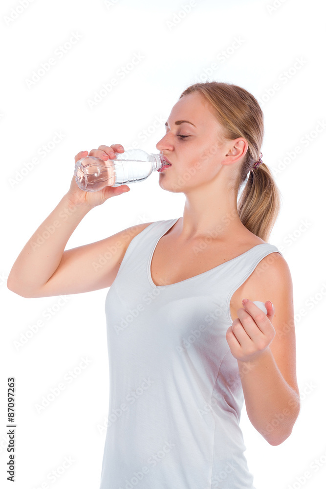Portrait of a young happy girl drinking water from bottle after fitness, isolated on a white background Portrait of a young happy girl drinking water from bottle after fitness, isolated on a white background