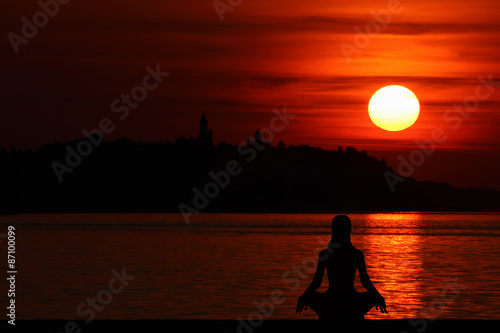 Woman doing Yoga at sunset