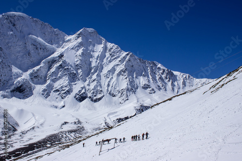 A group of tourists walking on the snow slope on a background of the peak "Seven" © pinguin3107
