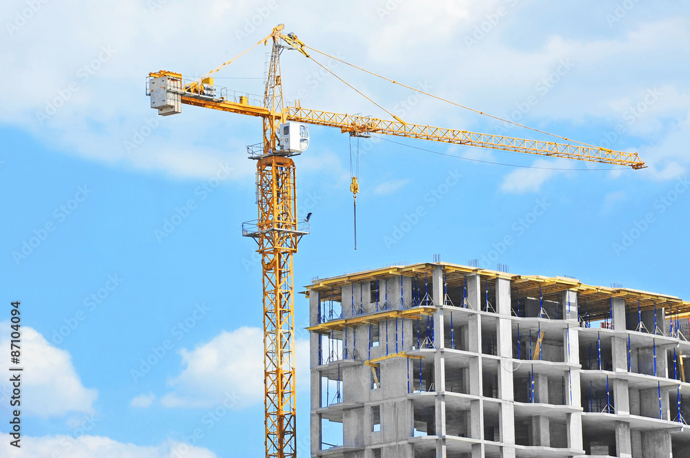 Crane and building construction site against blue sky