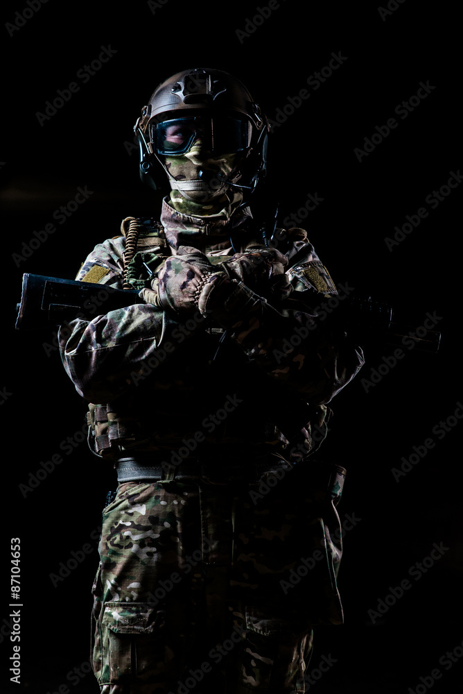 Armed ranger standing  and looking at the camera/Ranger in camouflage,mask and helmet  standing with rifle and looking at  camera on black background