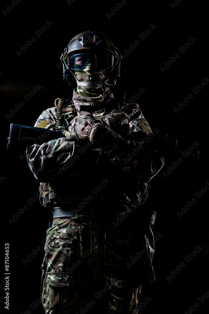 Armed ranger standing and looking at the camera/Ranger in camouflage,mask and helmet standing with rifle and looking at camera on black background Armed ranger standing and looking at the camera/Ranger in camouflage,mask and helmet standing with rifle and looking at camera on black background