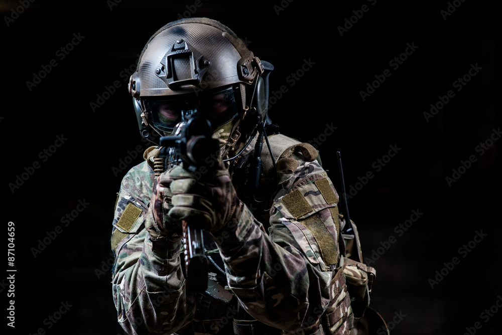 Fototapeta premium Armed soldier in camouflage aiming a rifle at you