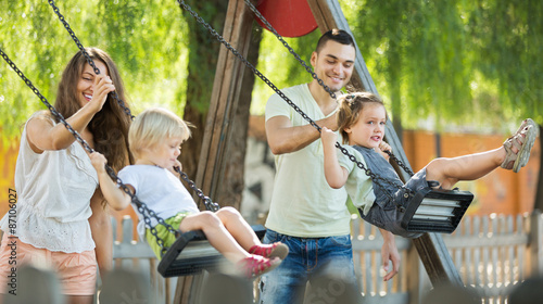 Parents swinging children