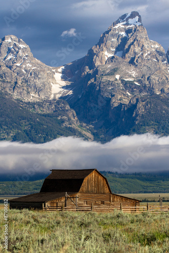 Iconic barn in Mormon Row with fog over the snake river and mountains in Grand Teton National Park in Wyoming