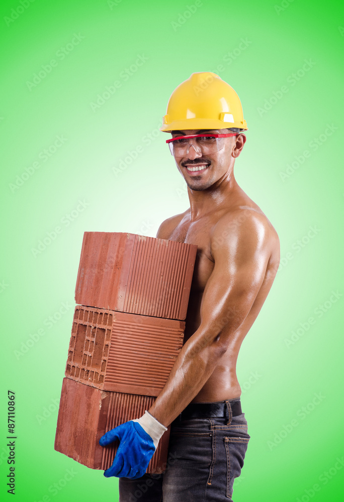 Muscular builder with bricks against gradient Muscular builder with bricks against gradient