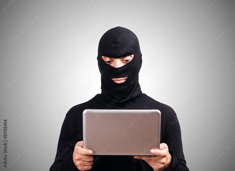 Hacker with computer wearing balaclava Hacker with computer wearing balaclava