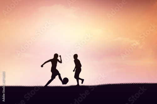 Silhouette of children playing soccer background sunset.