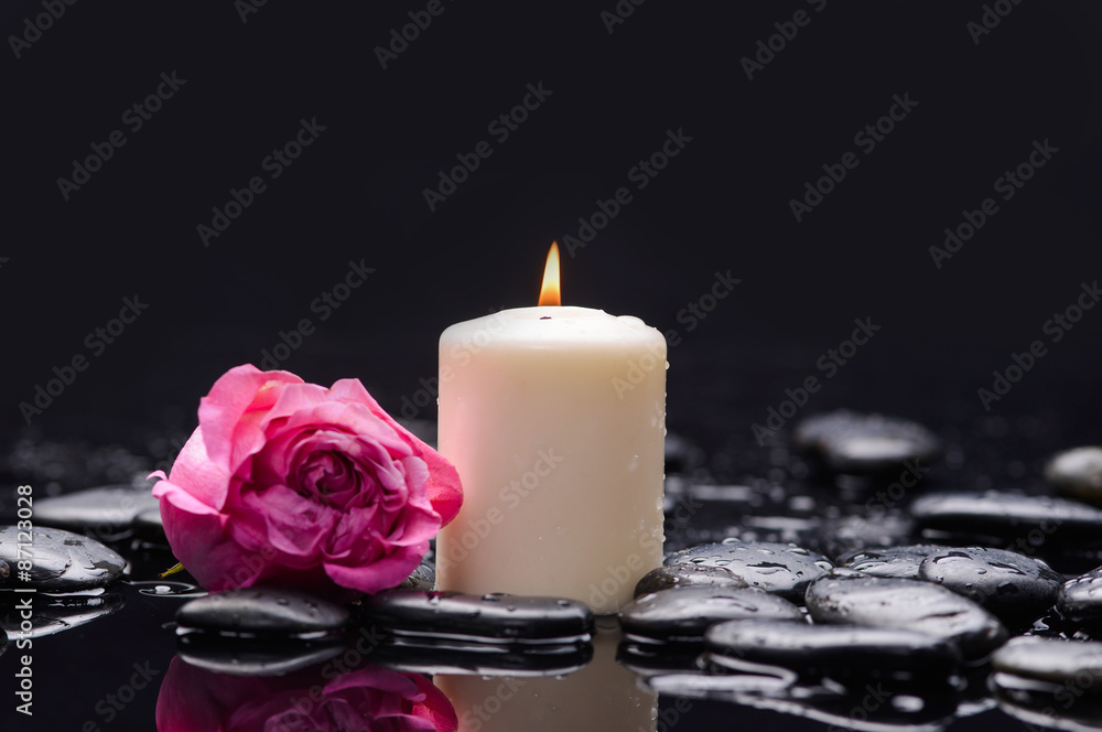 Beautiful pink rose with candle and therapy stones 