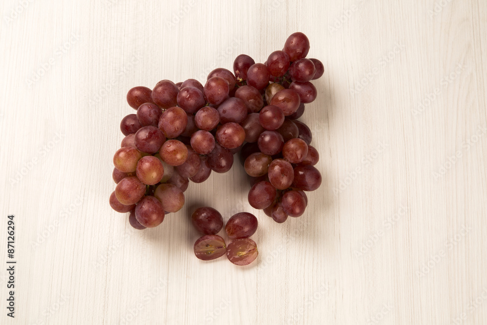 Some red grapes in a wooden pot over a wooden surface seen from