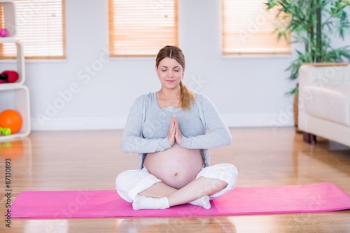 Pregnant woman doing yoga on exercise mat 