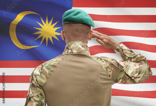 Dark-skinned soldier with flag on background - Malaysia