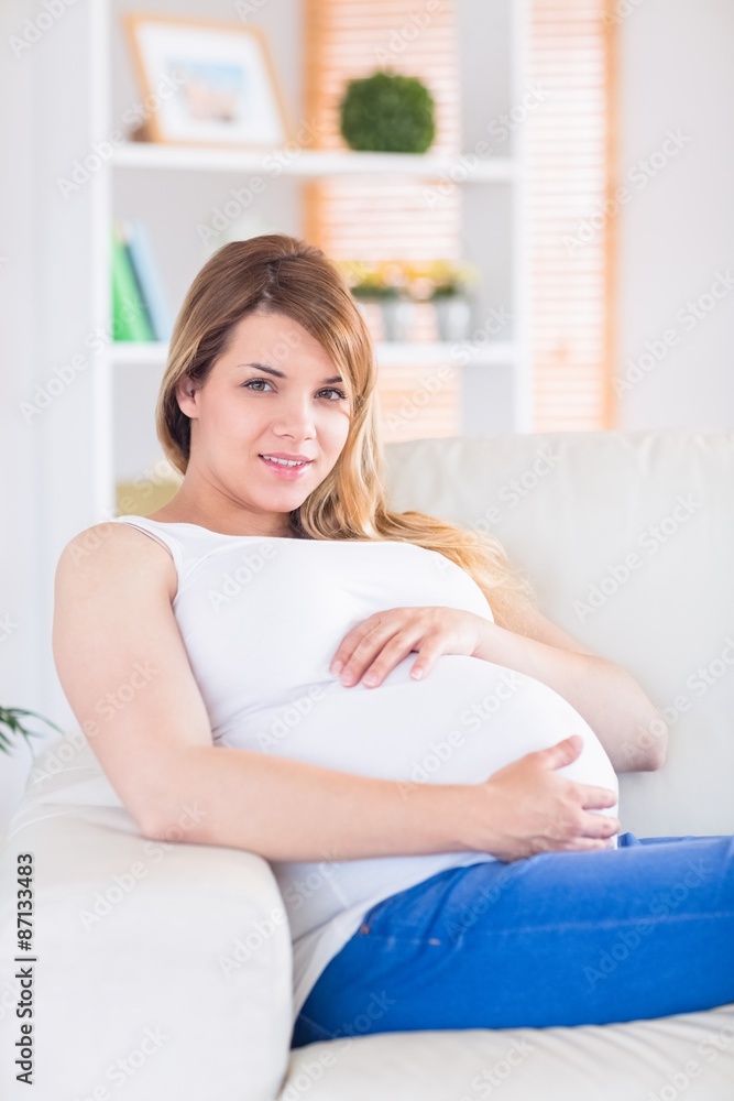 Pregnant woman looking at camera on the couch Pregnant woman looking at camera on the couch