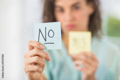 Smiling businesswoman holding yes and no sticks