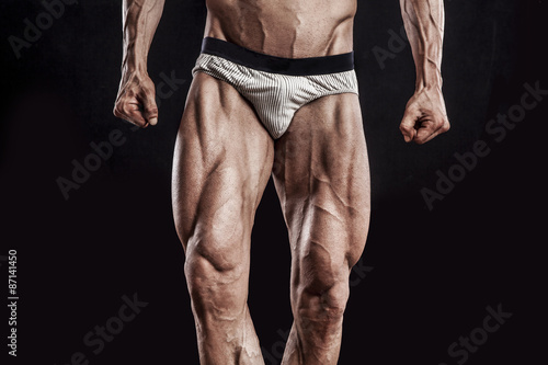 muscle man legs on black background, bodybuilding athlete portra
