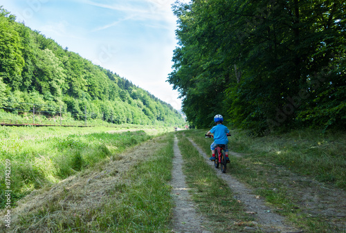 boy cycling in the shadow on the pathway near the river