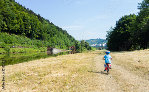 boy with helmet cycling alone on the terrain track near river