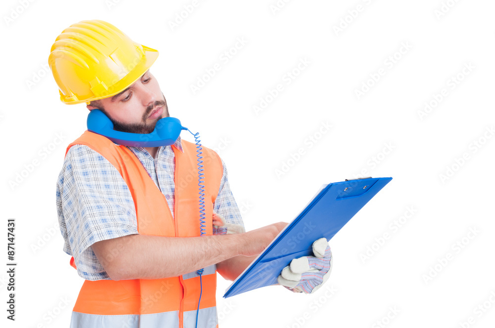 Busy builder using phone while holding clipboard Busy builder using phone while holding clipboard