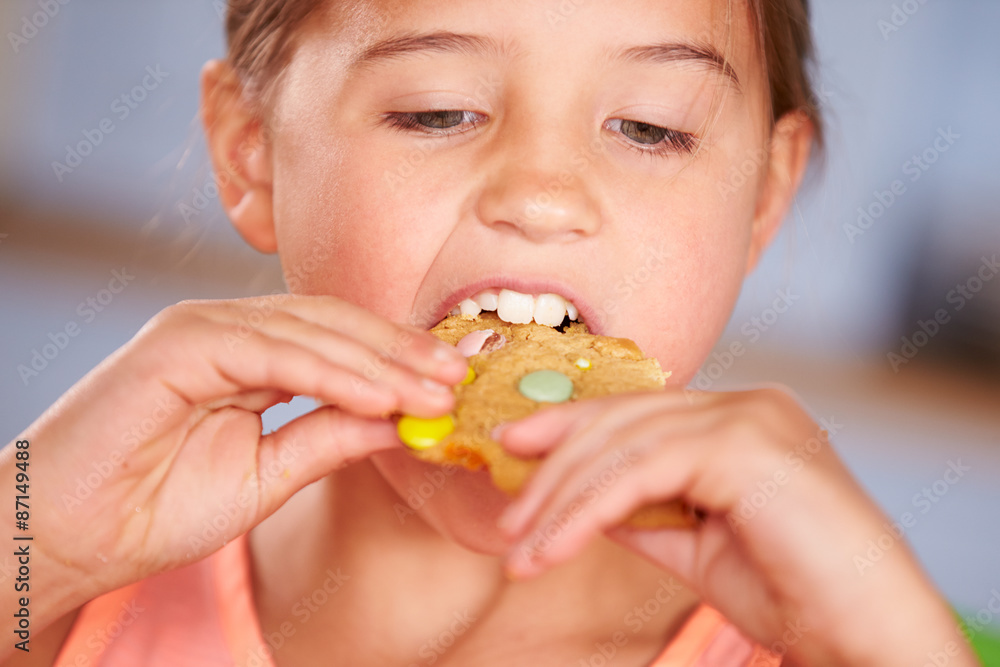 Close Up Of Young Girl Sitting At Table Eating Cookie Close Up Of Young Girl Sitting At Table Eating Cookie