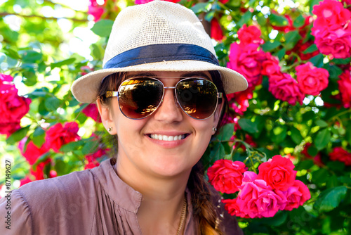 Smiling Woman Against Pretty Red Flower Plant