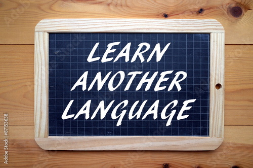 The phrase Learn Another Language in white text on a slate blackboard photo