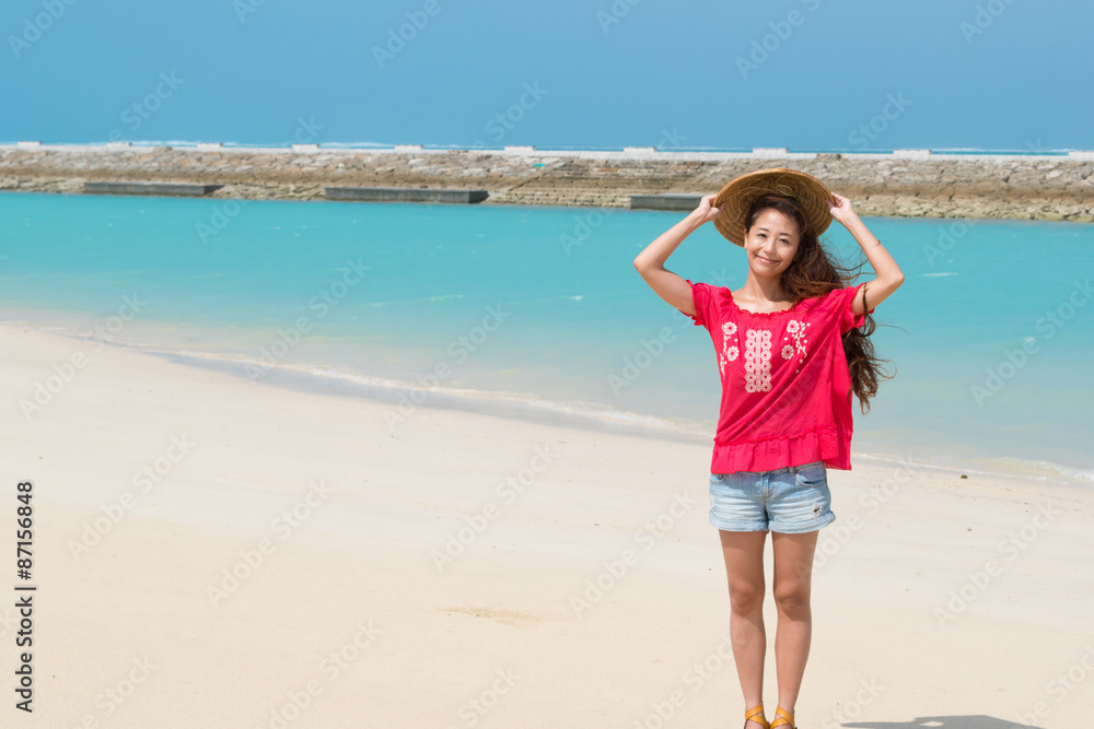 沖縄の美しい海をバックに麦わら帽子をかぶる女性(3)
