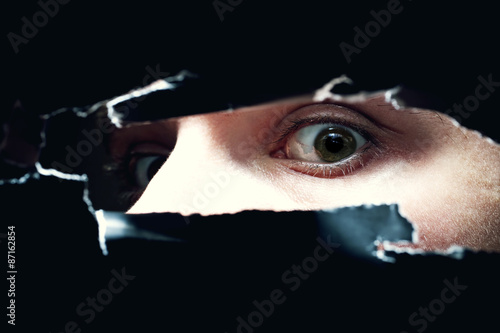 young man looking out of  hole in wall photo