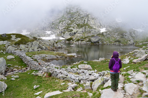 Young woman admiring a mountain lake in fog