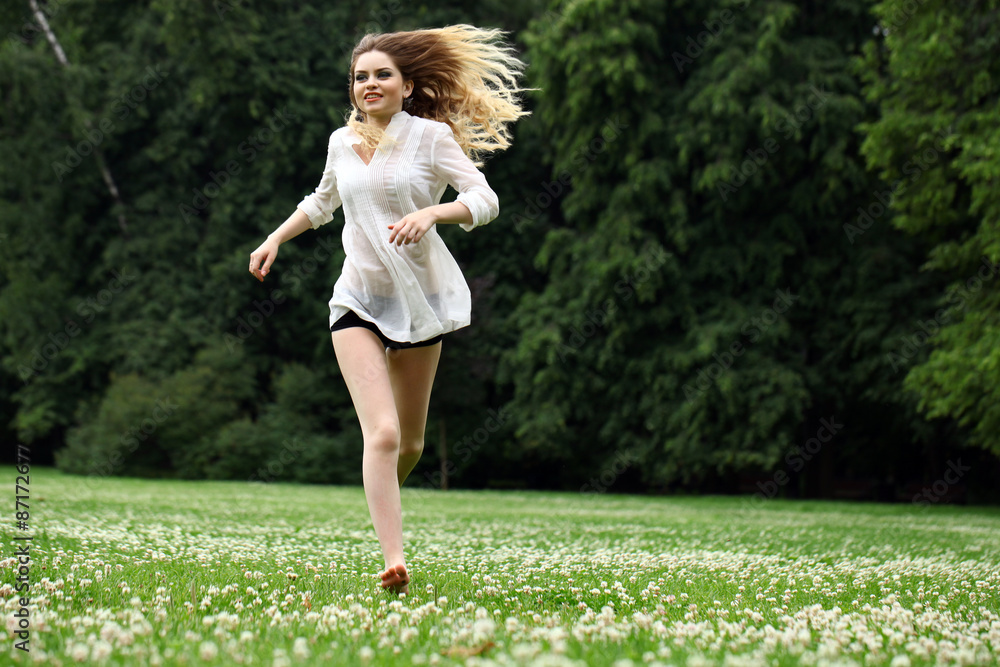 Young beautiful girl in the white shirt is running on the green Young beautiful girl in the white shirt is running on the green