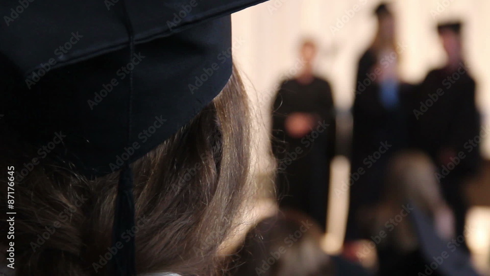 Girl in academic cap looking at students receiving diplomas, college ...