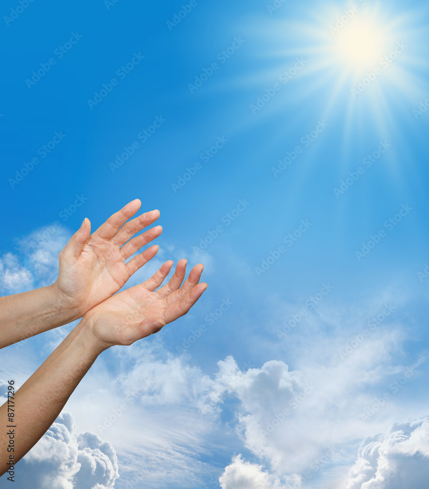 Divine Source - Female hands reaching up towards a bright sun burst on a blue sky background with fluffy clouds and plenty of copy space Divine Source - Female hands reaching up towards a bright sun burst on a blue sky background with fluffy clouds and plenty of copy space