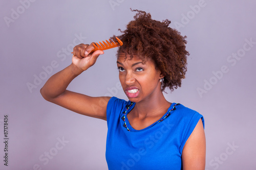 Young African American woman combing her frizzy afro hair - Blac