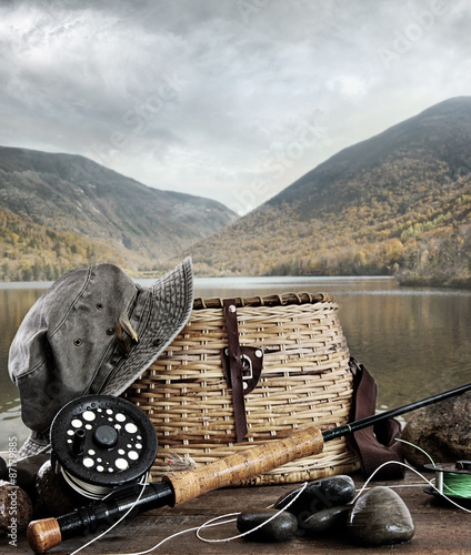 Fly rod with creel and equipment on wood