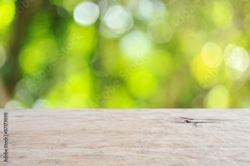 Top wooden table with sunny abstract green nature background, bl