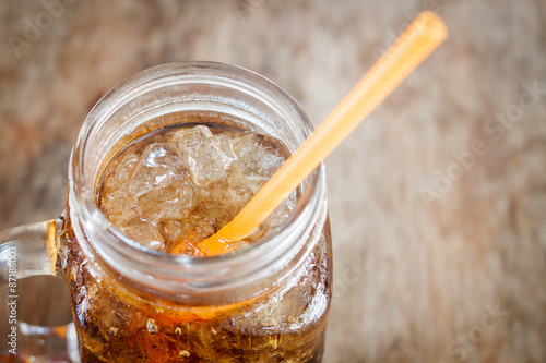 Glass of cola with ice on wooden table