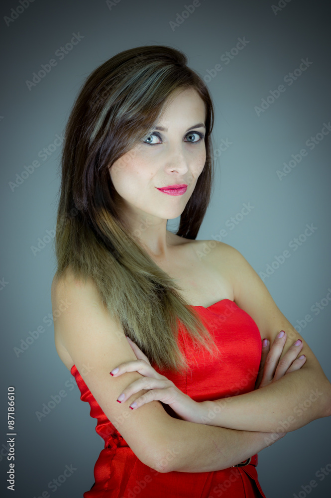 Hispanic female model posing for camera in studio with arms crossed looking towards lens Hispanic female model posing for camera in studio with arms crossed looking towards lens