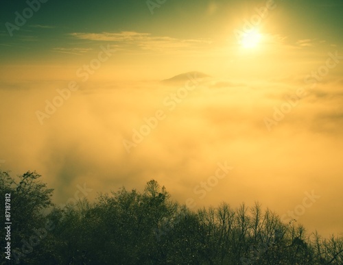 Magnificent heavy mist in landscape. Autumn fogy sunrise in a countryside. Hill increased from fog.