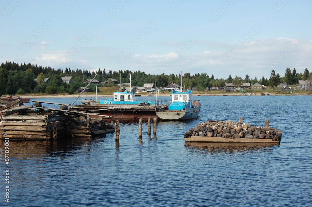 Two fishing motor boats are docked on a lake in remote taiga village.