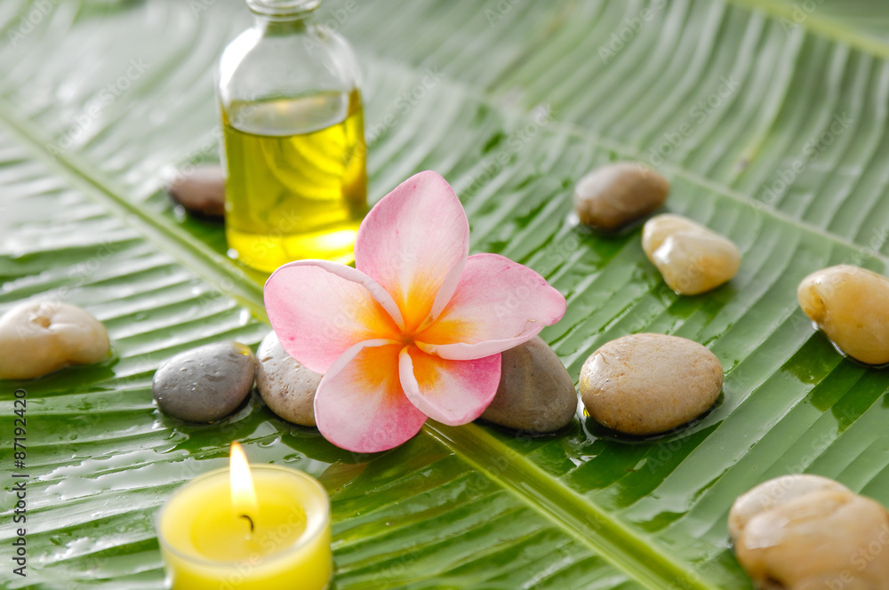 frangipani and stones ,oil with burning candle on wet banana leaf frangipani and stones ,oil with burning candle on wet banana leaf