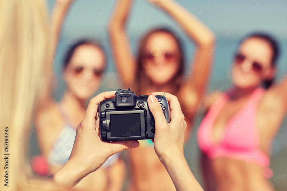 close up of smiling women photographing on beach