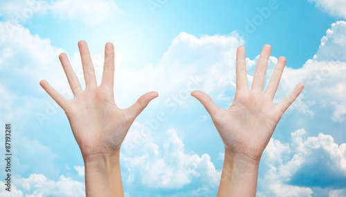 two woman hands making high five over blue sky