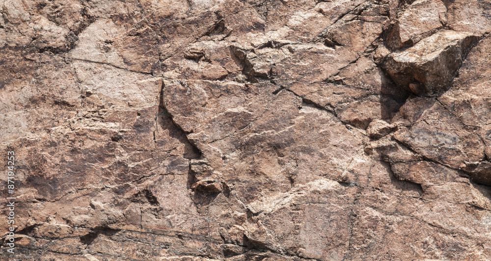 Fototapeta premium Rough brown rock wall, stone texture